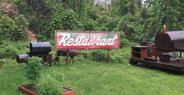 Silver Dollar Cafe signage sits in the garden of All Souls Pizza, in the River Arts Restaurant. Photo by Nan K. Chase